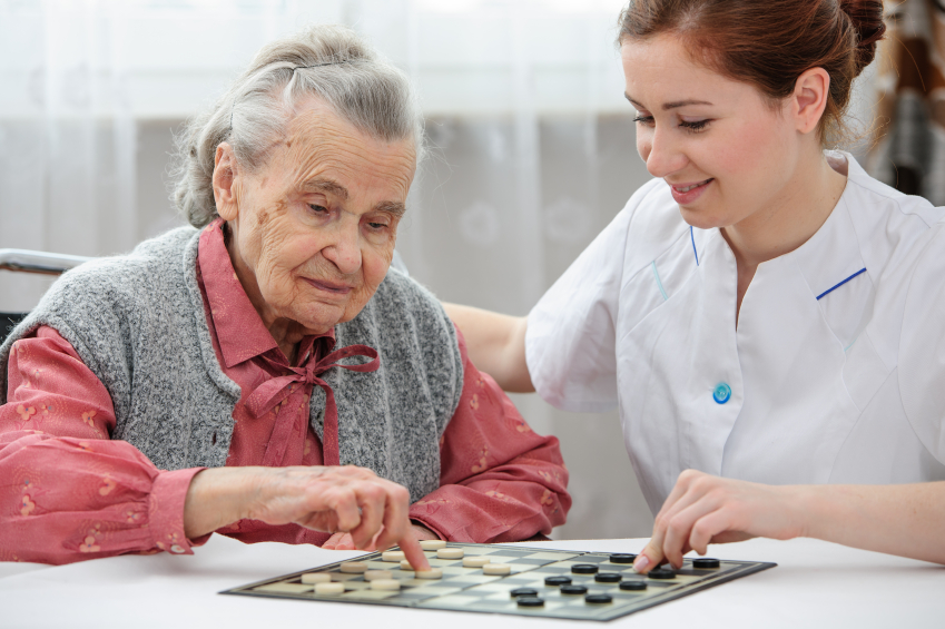 Senior woman playing checkers with a nurse in a retirement home
