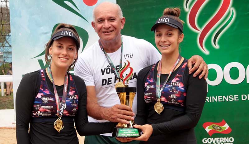 Acompanhadas pelo técnico Cezão (C), a dupla Helena (D) e Larissa (E) foram campeãs no vôlei de praia | Foto Divulgação