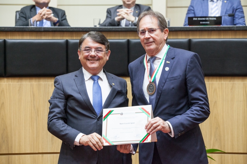 Deputado Maurício Peixer (esq.) entrega homenagem ao presidente da Fiesc, Mario Aguiar

Divulgação/Alesc
